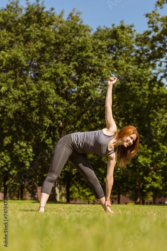 Pretty athletic redhead stretching in park
