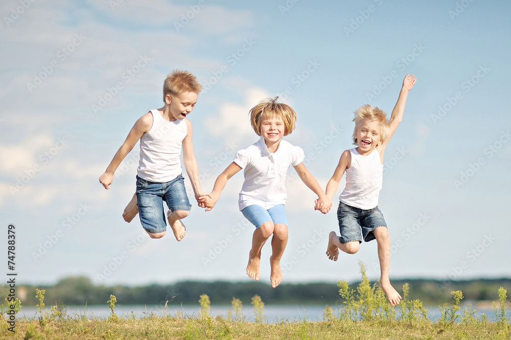 three children playing on meadow in summer