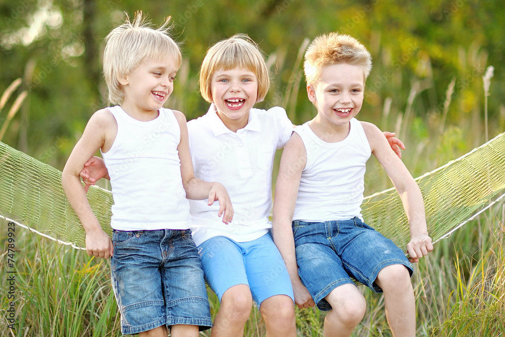 Fototapeta premium three children playing on meadow in summer