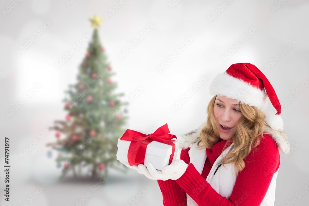 Composite image of surprised blonde in santa hat holding gift Composite image of surprised blonde in santa hat holding gift