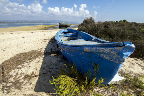 View of an old abandoned boat stranded on dry sand at the beach.