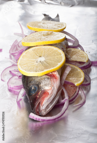 Fish prepared for roasting on the foil with lemon and onion photo