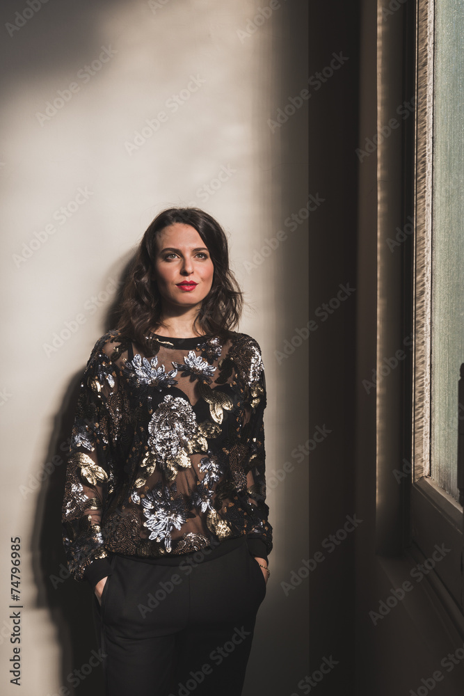 Portrait of a beautiful young brunette posing beside a window