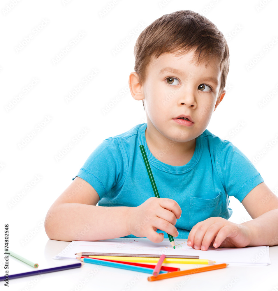 Cute boy is drawing using color pencils Cute boy is drawing using color pencils