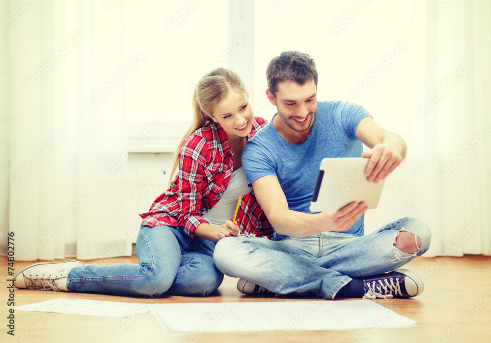 smiling couple looking at tablet pc at home