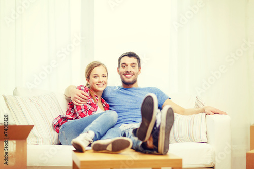 smiling couple relaxing on sofa in new home