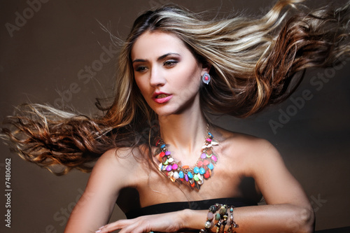 Fashion model with long curly hair posing in exclusive jewelry