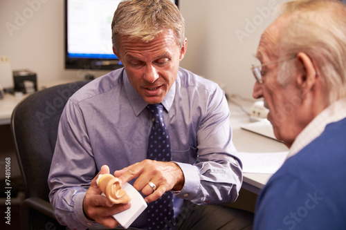Doctor Showing Senior Male Patient Model Of Human Ear photo