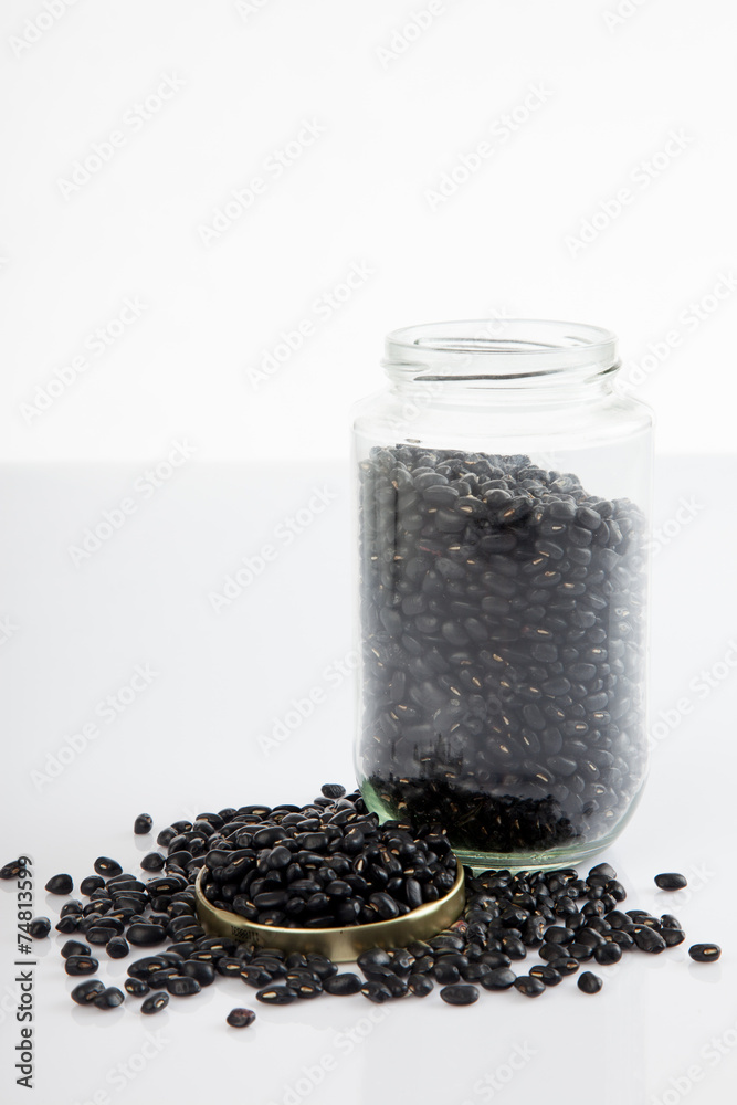 Black beans in a jar on white table with lid off Black beans in a jar on white table with lid off