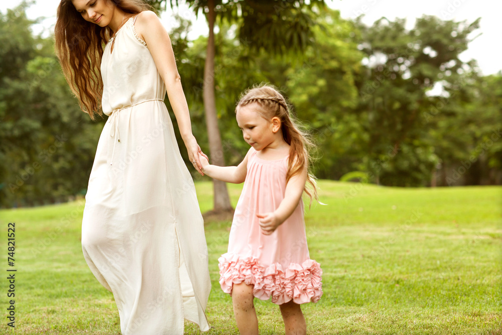 mother and daughter walking in the park, happy at sunset