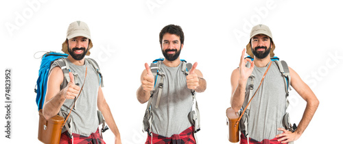 Backpacker with thumb up over white background © luismolinero