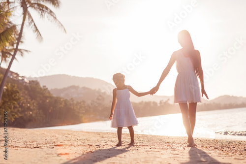 Mother and daughter happily running along the beach, Thailand