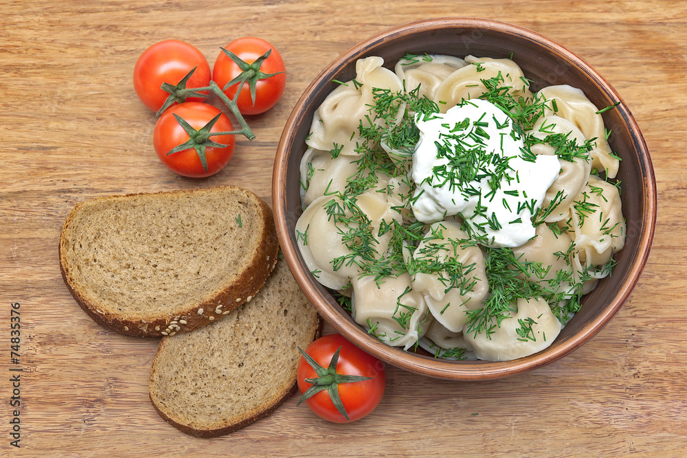 dumplings with fresh herbs and sour cream in a dish, cherry toma