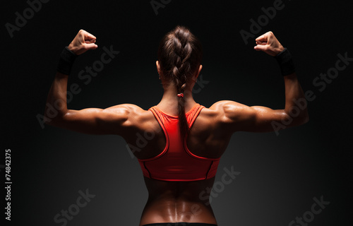 Obraz na plátně Athletic young woman showing muscles of the back