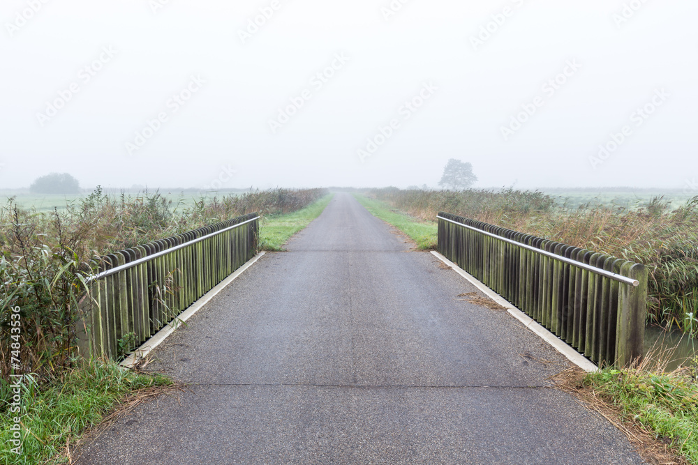Bridge over water in a misty morning rural landscape in the Neth Bridge over water in a misty morning rural landscape in the Neth