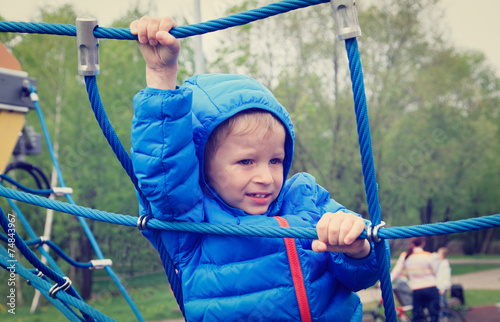 little boy climbing rope on the playground