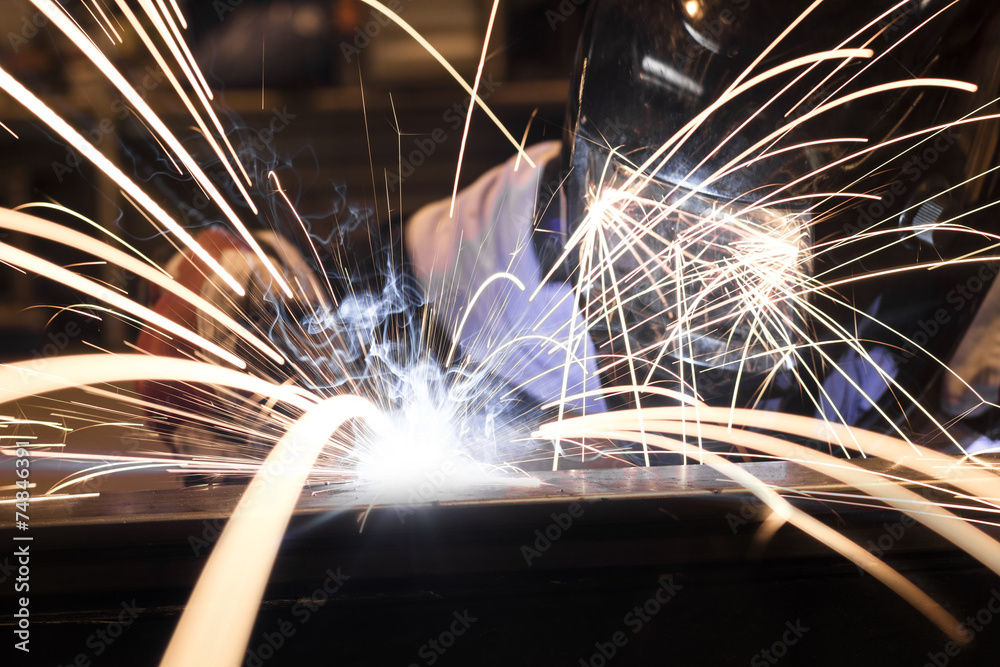 Employee welding steel using MIG/MAG welder. - obrazy, fototapety, plakaty 