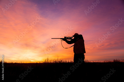 Rifle hunter Silhouetted at Sunrise