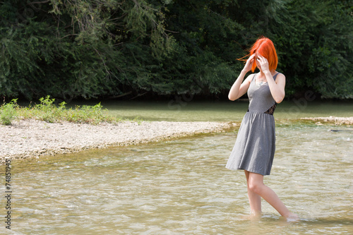 Fototapeta Naklejka Na Ścianę i Meble -  Pretty red hair girl walking in river