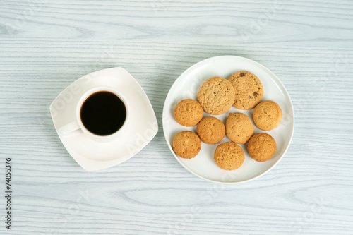 Coffee cup with oatmeal cookies on the white plate