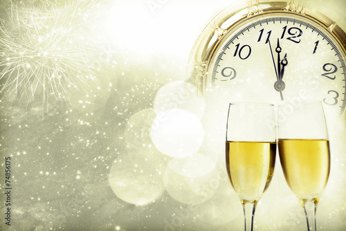 Champagne against fireworks, clock close to midnight and sparkli