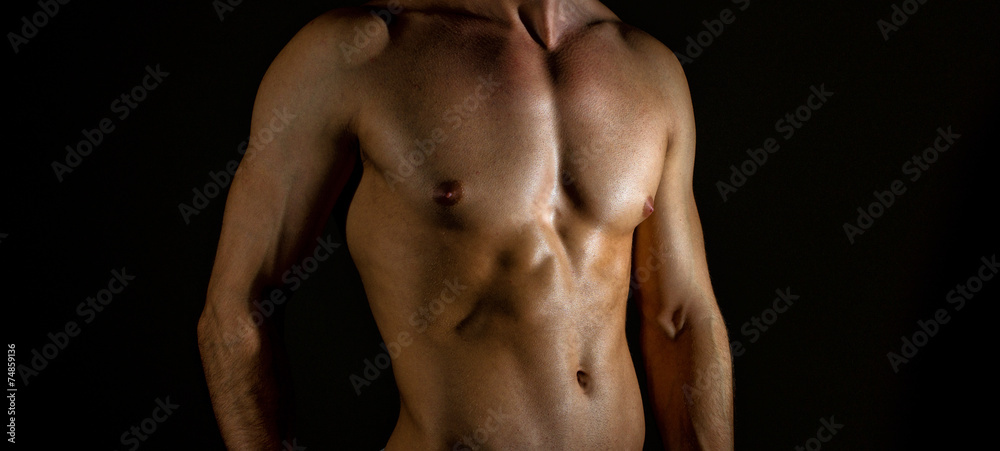 Unrecognizable muscular male body on black background.