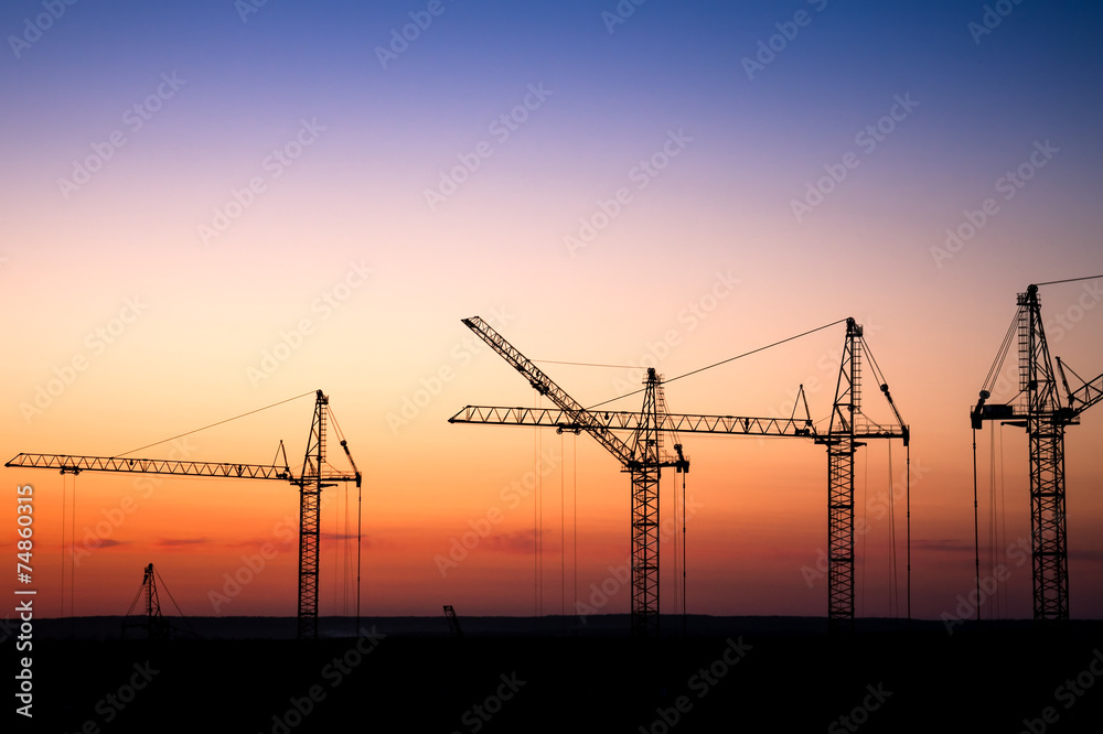 construction site with cranes against a sunset sky