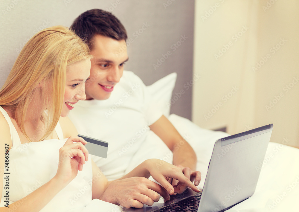 couple in bed with laptop computer and credit card couple in bed with laptop computer and credit card