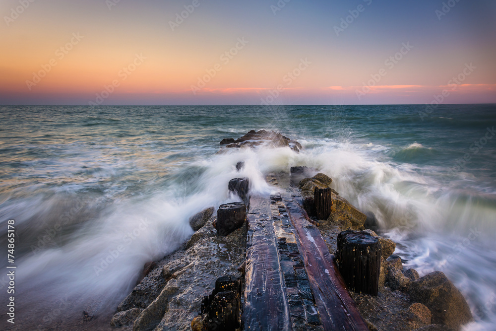 Fototapeta premium Waves and a jetty at sunset in the Atlantic Ocean at Edisto Beac