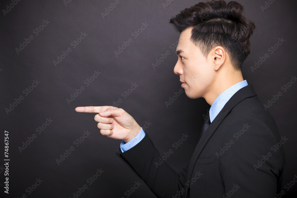 side view angry businessman standing before black background