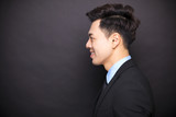 side view smiling businessman standing before black background