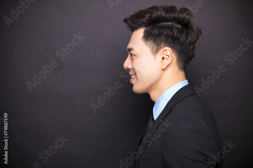 Fototapeta Naklejka Na Ścianę i Meble -  side view smiling businessman standing before black background
