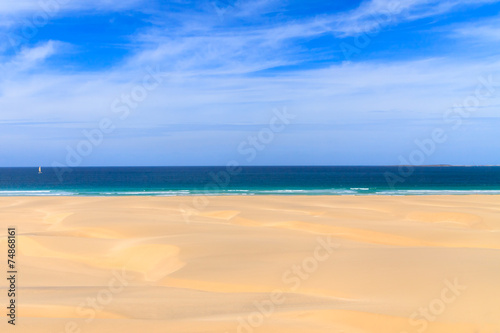 Sand dunes near to the ocean with cloudy blue sky, Boavista, Cap