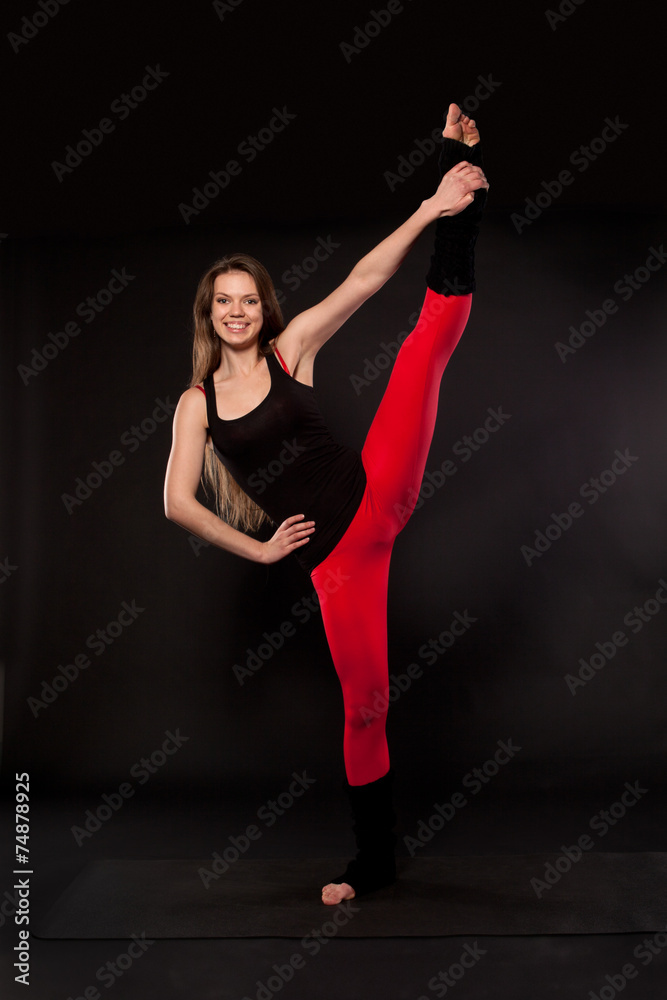 Young woman doing yoga on a black background