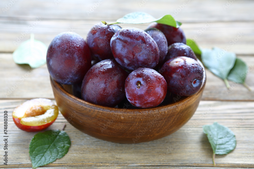 fresh juicy plums in brown bowl