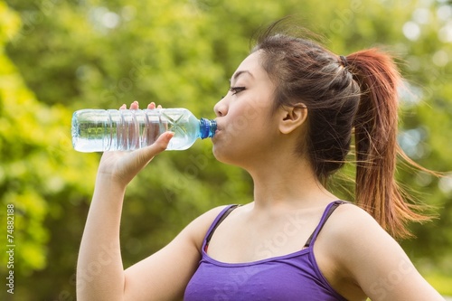 Healthy woman drinking water in park