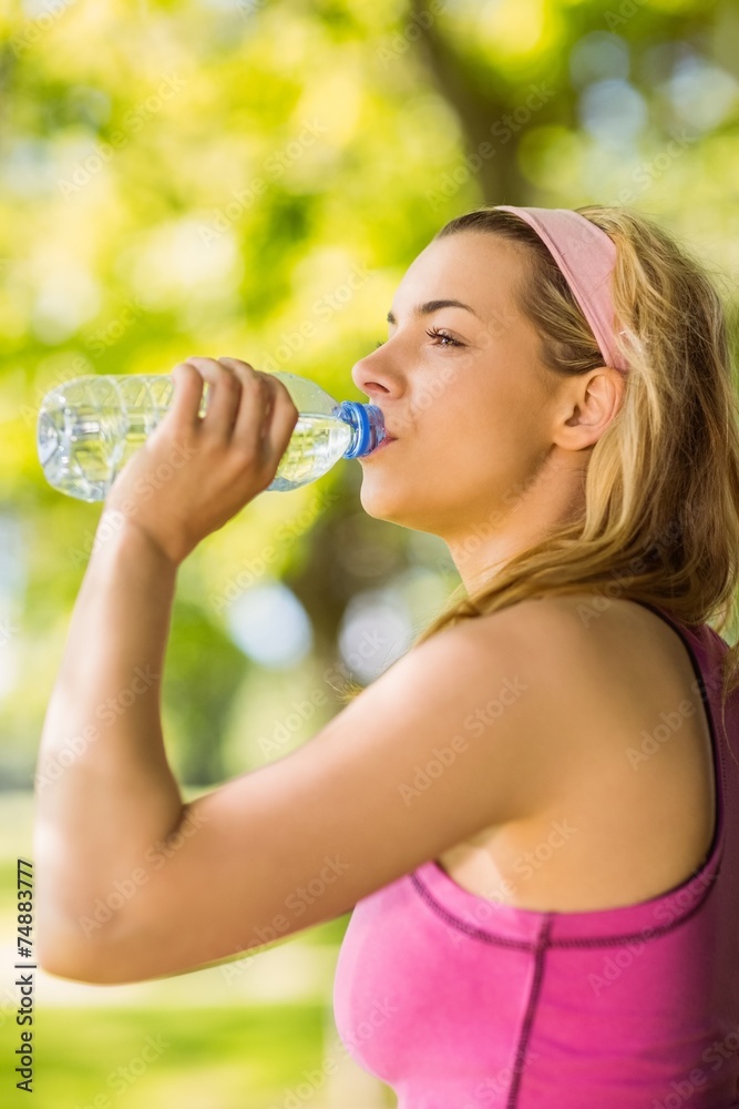 Fit blonde leaning against tree drinking water Fit blonde leaning against tree drinking water