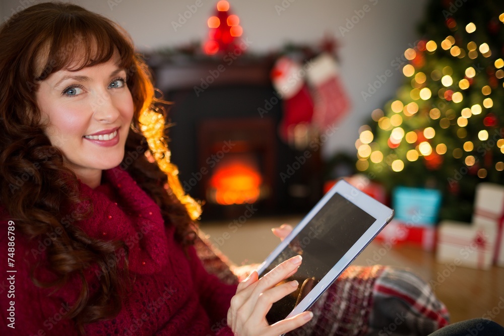 Cheerful redhead using tablet at christmas Cheerful redhead using tablet at christmas
