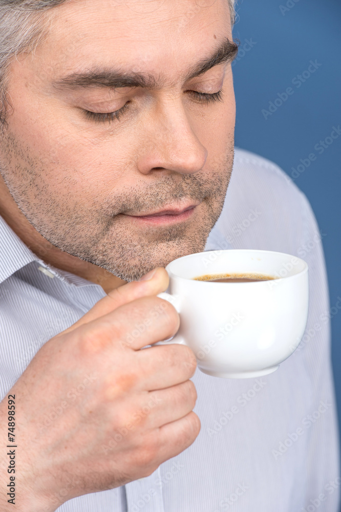 Happy adult man drinking coffee on blue. Happy adult man drinking coffee on blue.