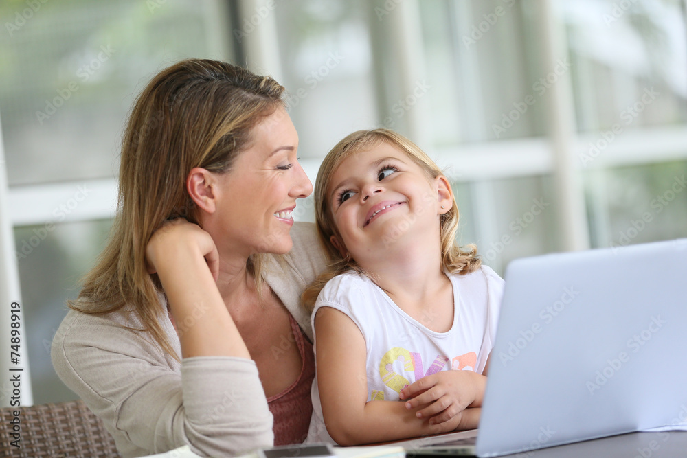 Little girl looking at laptop computer with her mom Little girl looking at laptop computer with her mom