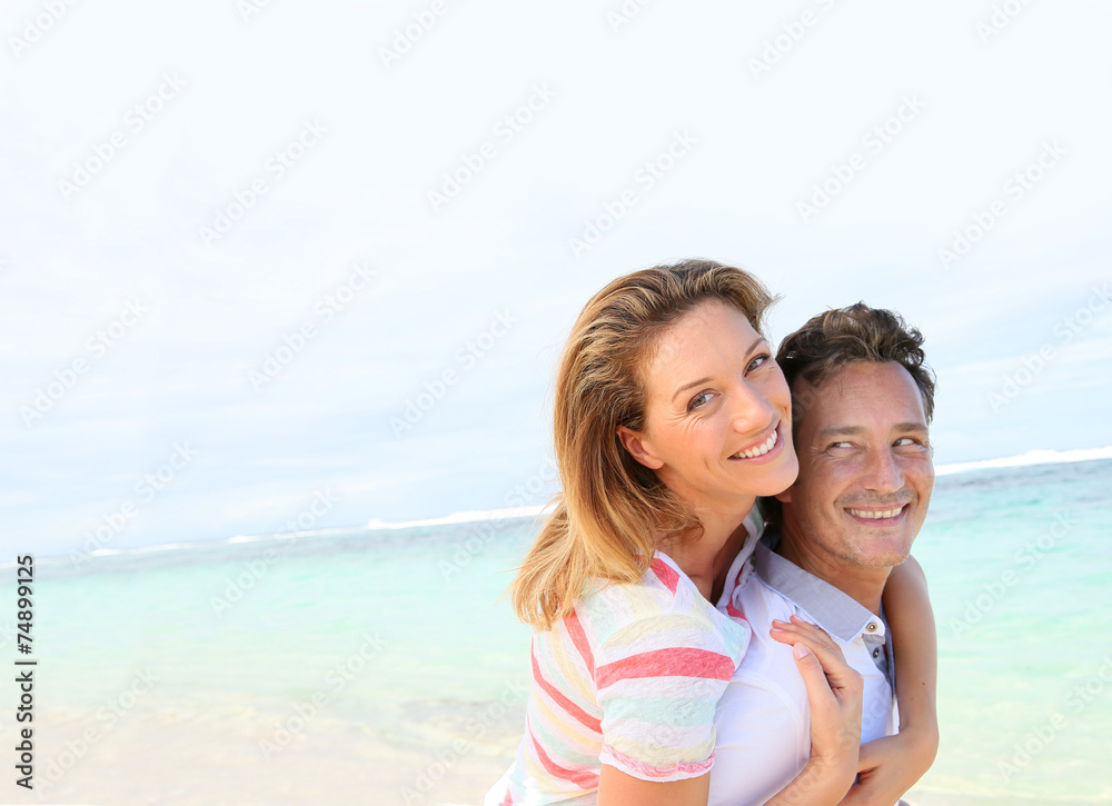 Man giving piggyback ride to girlfriend at the beach