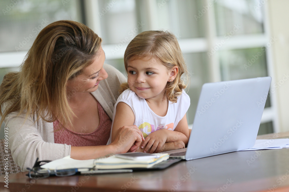 Little girl looking at laptop computer with her mom Little girl looking at laptop computer with her mom