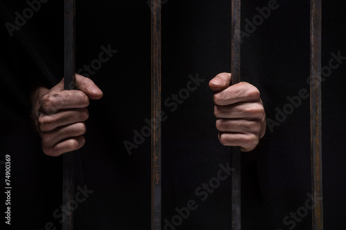 closeup on hands of man sitting in jail.