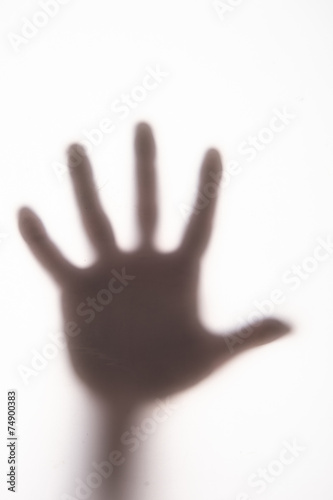 Silhouetted hand on frosted glass.