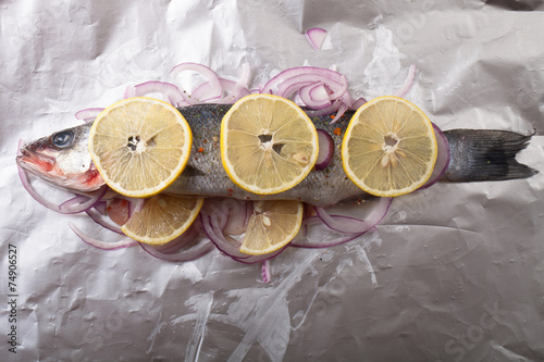 Fish prepared for roasting on the foil with lemon and onion photo