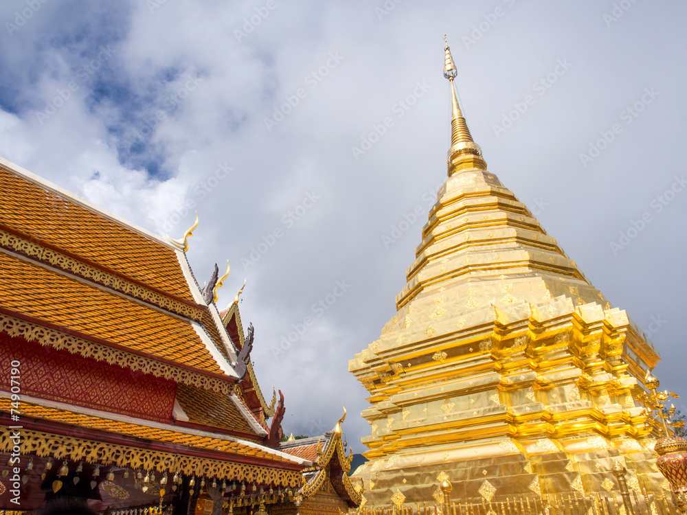 Fototapeta premium Golden pagoda of Wat Phra That Doi Suthep under cloudy blue sky