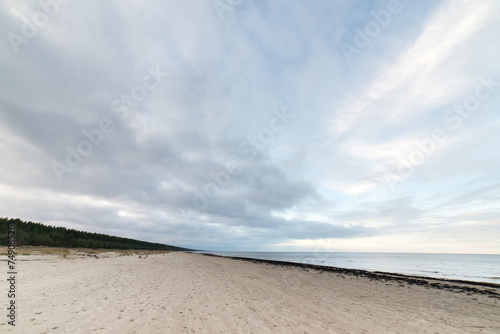 baltic beach in fall with clouds and waves towards deserted dune