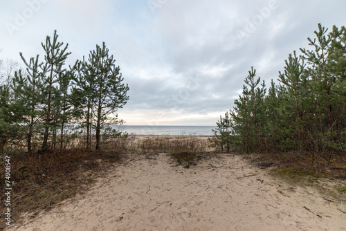 baltic beach in fall with clouds and waves towards deserted dune