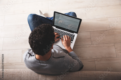 Young man sitting on floor and using notebook. photo