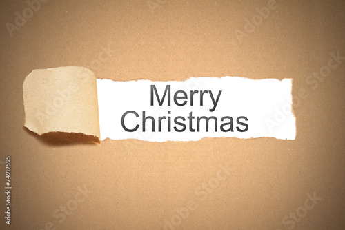brown paper torn to reveal merry christmas